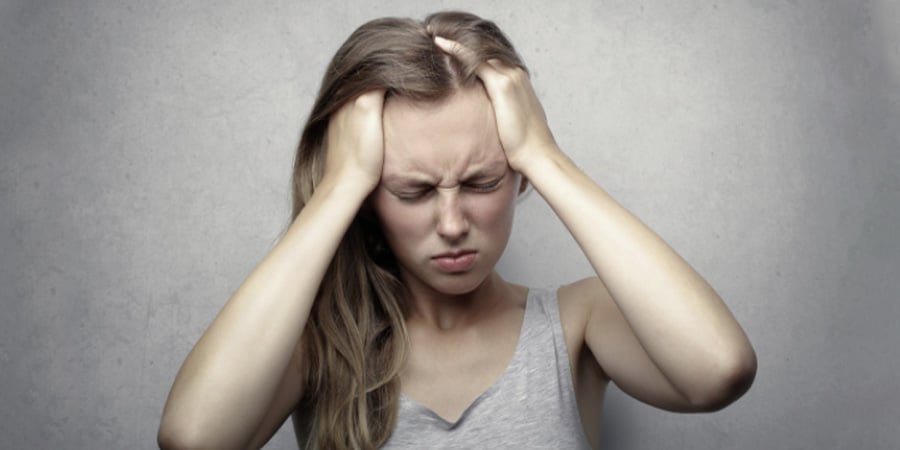Frau leidet unter starken Kopfschmerzen und hält Hände an den Kopf